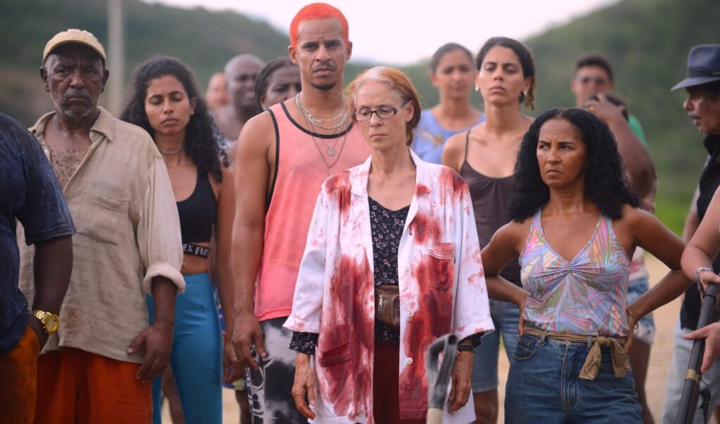 Moradores de Bacurau reunidos em uma estrada do sertão, alguns com roupas manchadas de sangue, em cena do filme de Kleber Mendonça Filho e Juliano Dornelles.