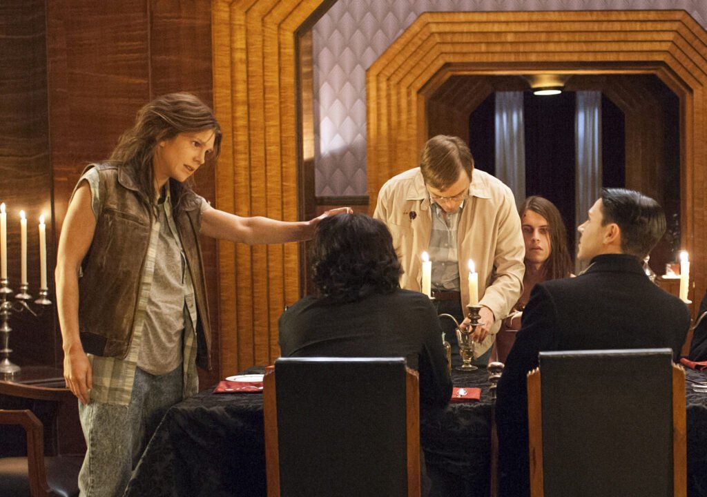 Personagens reunidos à mesa em uma cena de Devil’s Night, de American Horror Story.