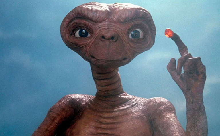 E.T., o extraterrestre do filme de Steven Spielberg, com o dedo iluminado diante de um fundo azul.